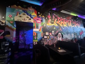 Interior booth area at Rad Bar with colorful murals, graffiti-style wall art, photo collages, and dark seating.