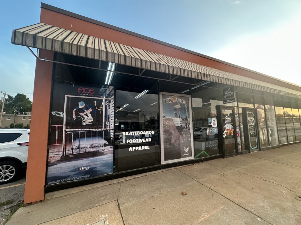 Exterior storefront of Money Ruins Everything in Oklahoma City with window signs for skateboards, footwear, and apparel.