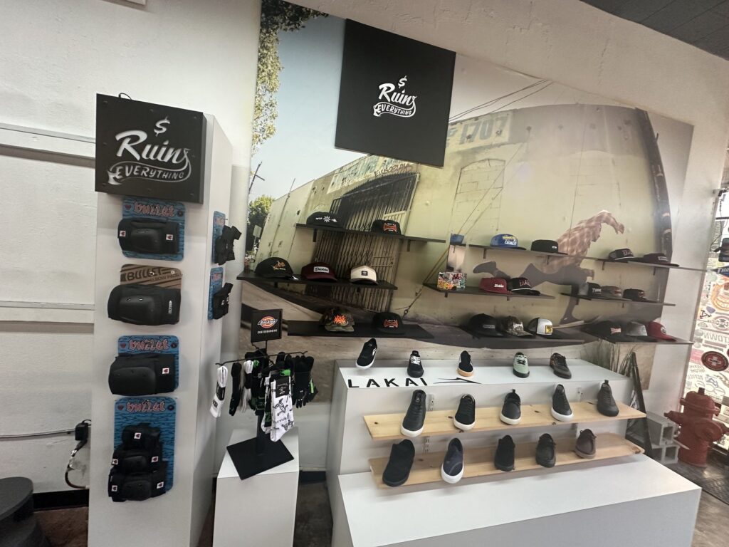 Shoe and hat display inside Money Ruins Everything with shop signage and skate accessories.