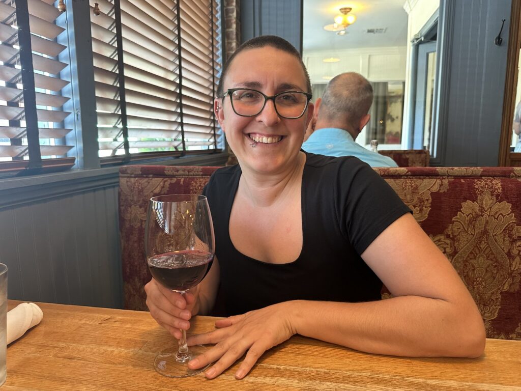 A diner smiles with a glass of red wine inside Pizzeria Gusto in Oklahoma City.