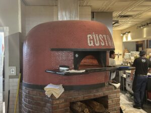 Large red wood-fired pizza oven inside Pizzeria Gusto in Oklahoma City.