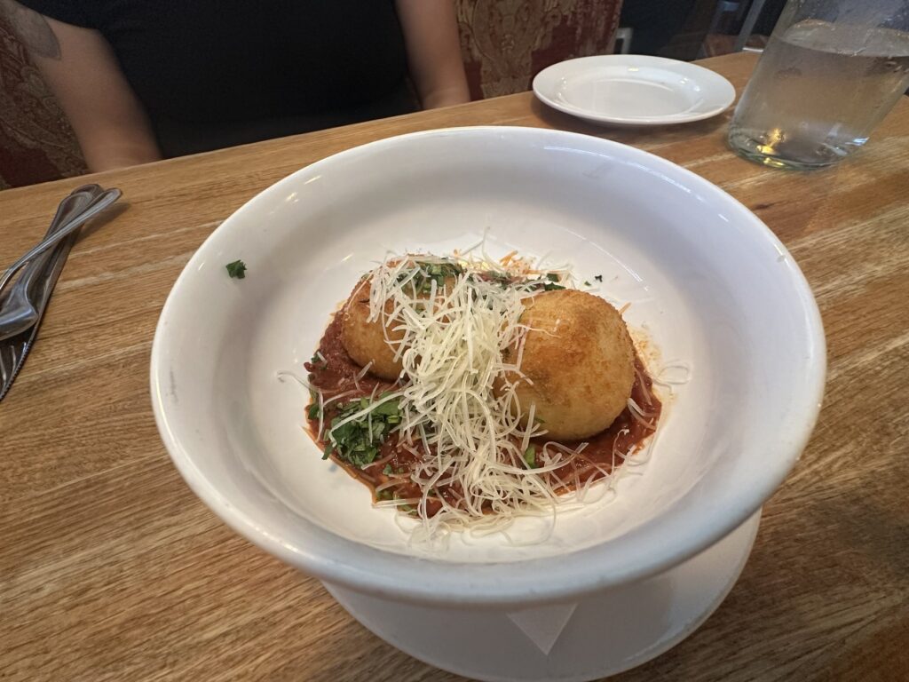 Fried arancini served over red sauce with grated cheese at Pizzeria Gusto.