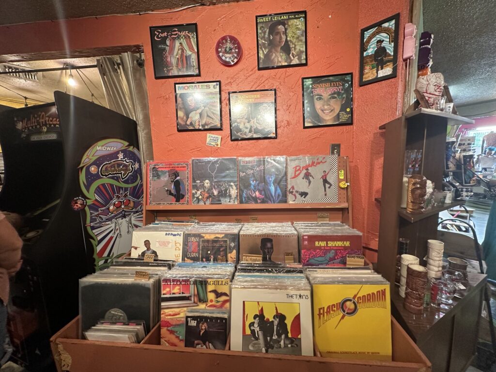 Vinyl records, framed album covers, glassware, and a retro arcade cabinet inside Dig It in Oklahoma City.