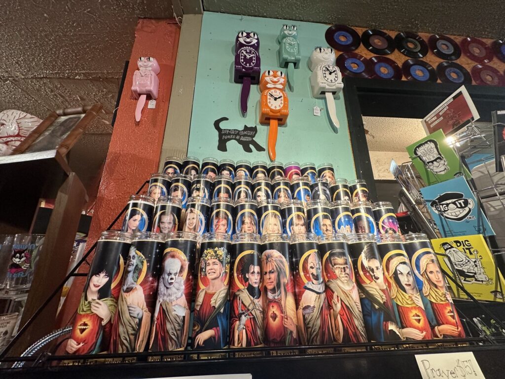 Novelty celebrity prayer candles displayed below colorful cat clocks inside Dig It in Oklahoma City.