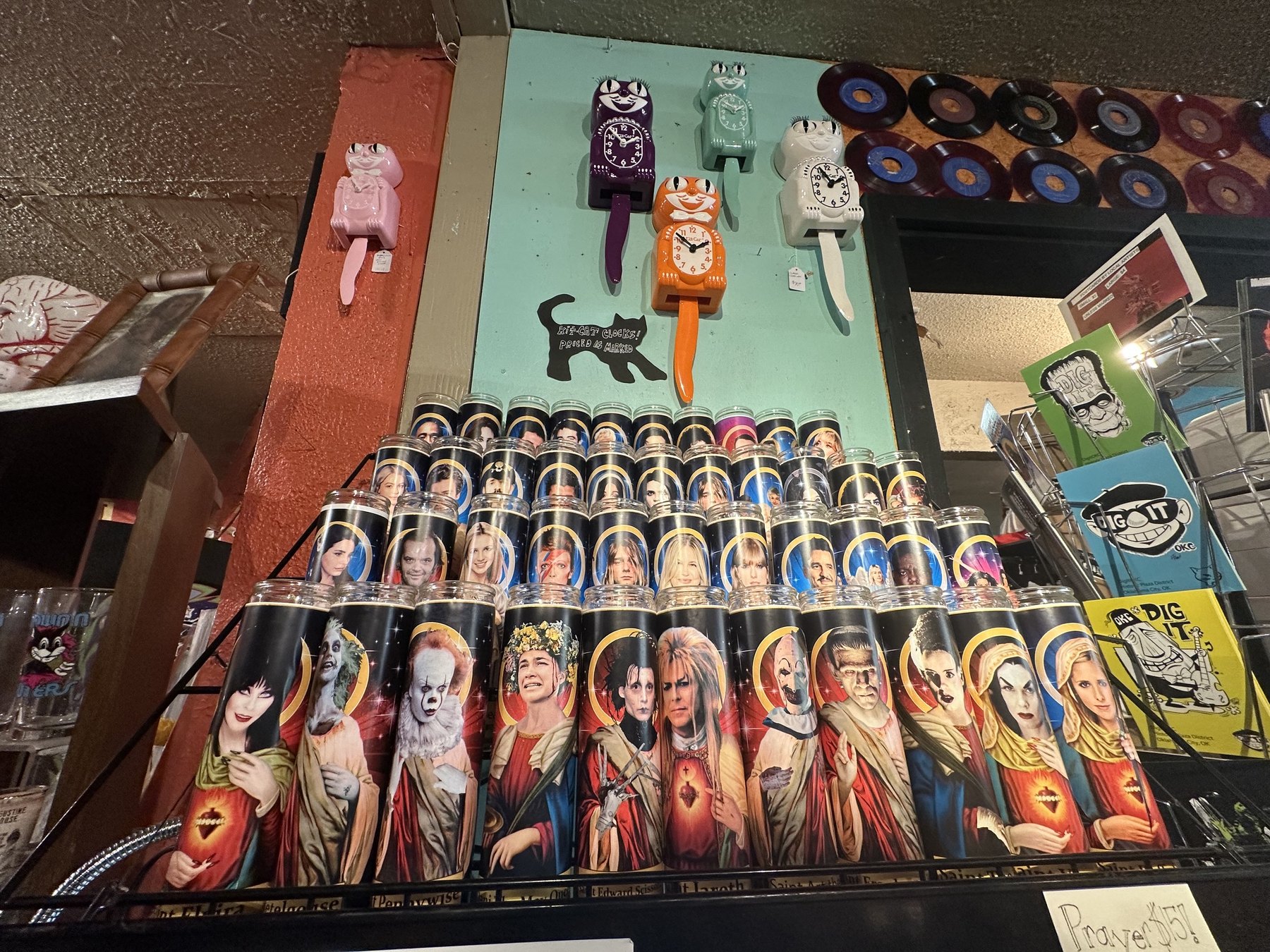 Novelty celebrity prayer candles displayed below colorful cat clocks inside Dig It in Oklahoma City.