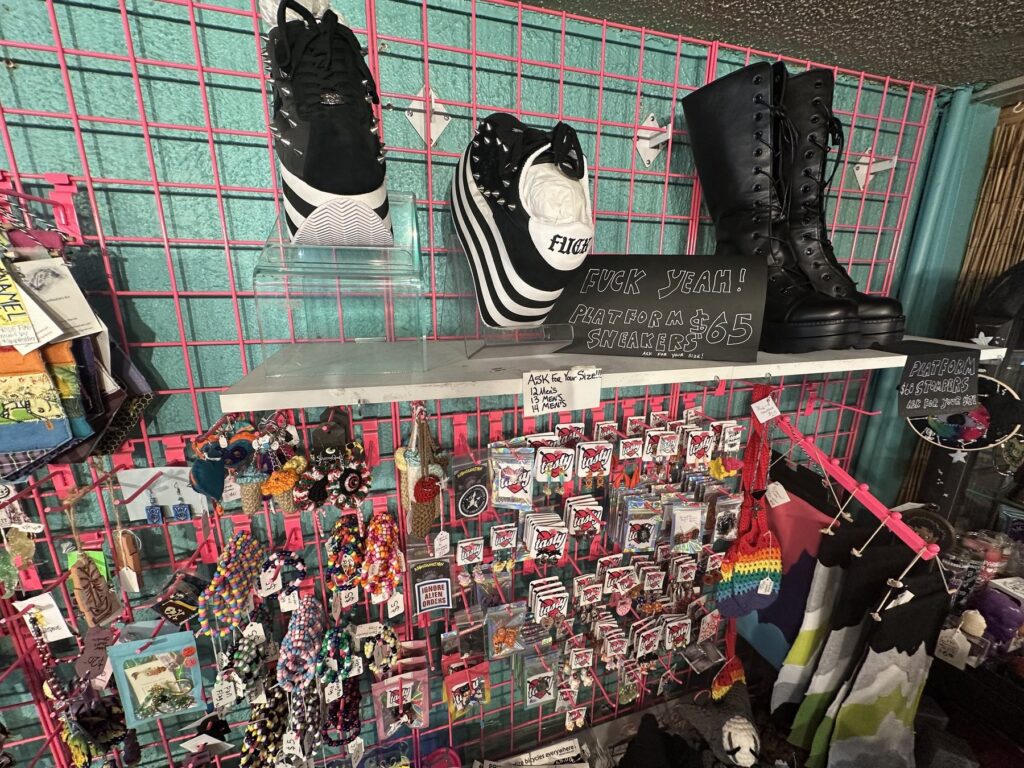 Platform sneakers, black lace-up boots, earrings, and accessories displayed on a pink grid wall at Dig It.