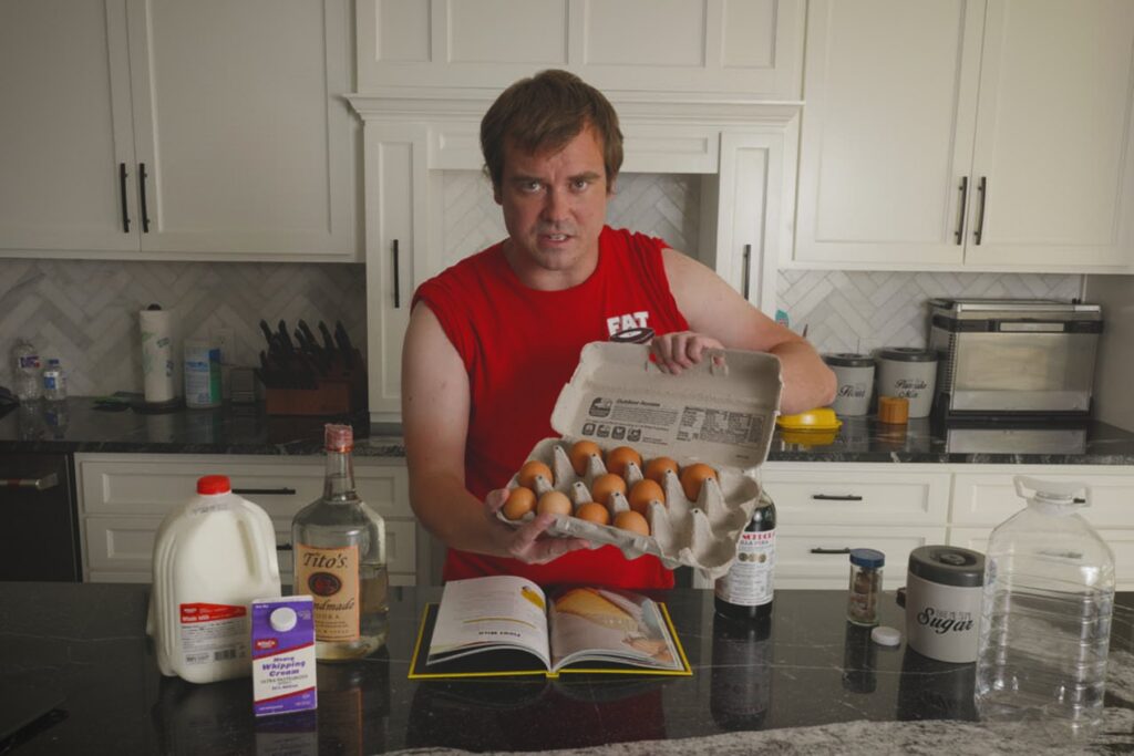 Cook holding an open carton of eggs while preparing Fight Milk from a cookbook recipe.