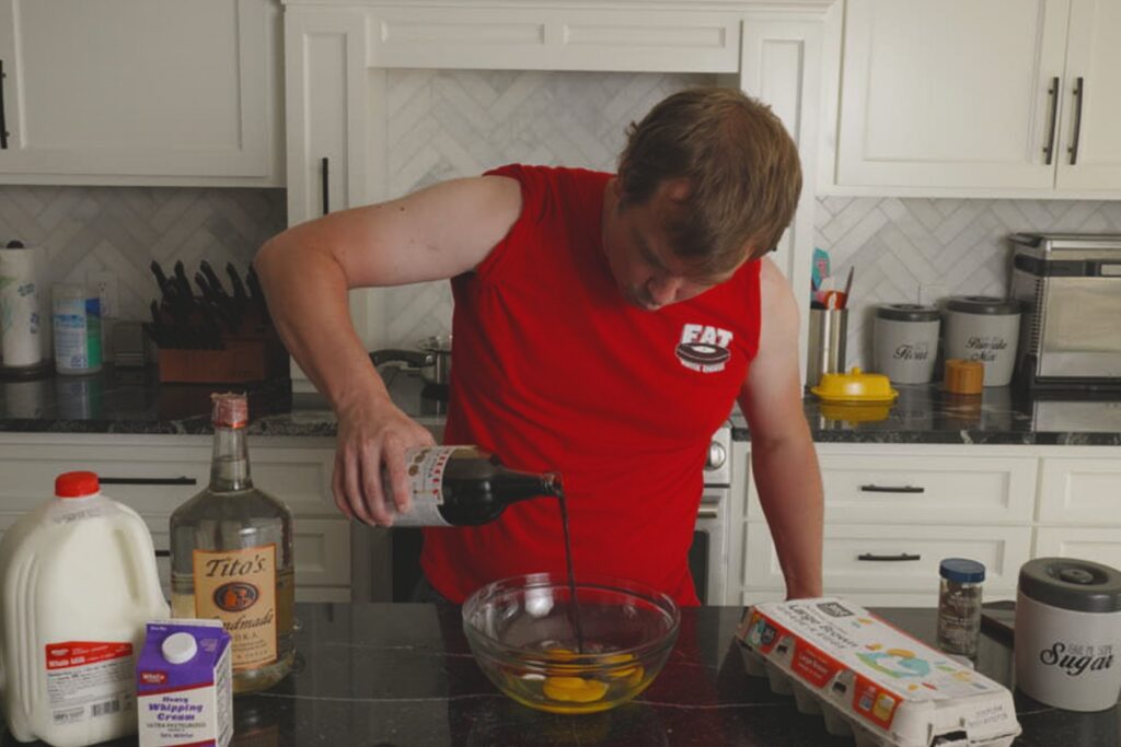 Cook pouring a dark liquid into a bowl of eggs while preparing homemade Fight Milk.