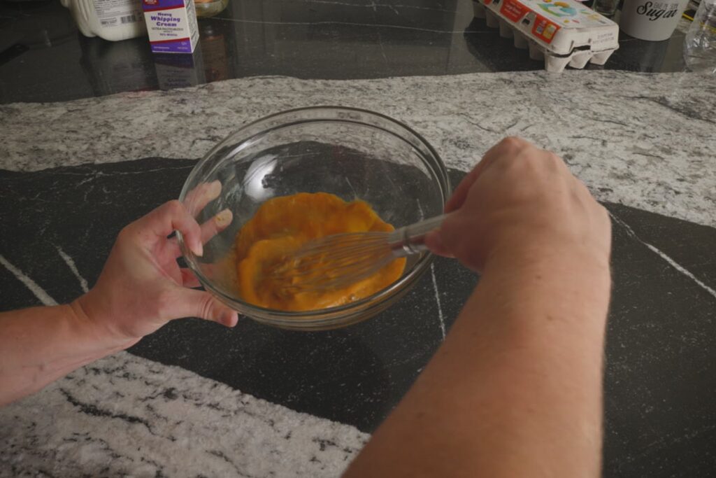 Close-up of eggs being whisked in a glass bowl for homemade Fight Milk.