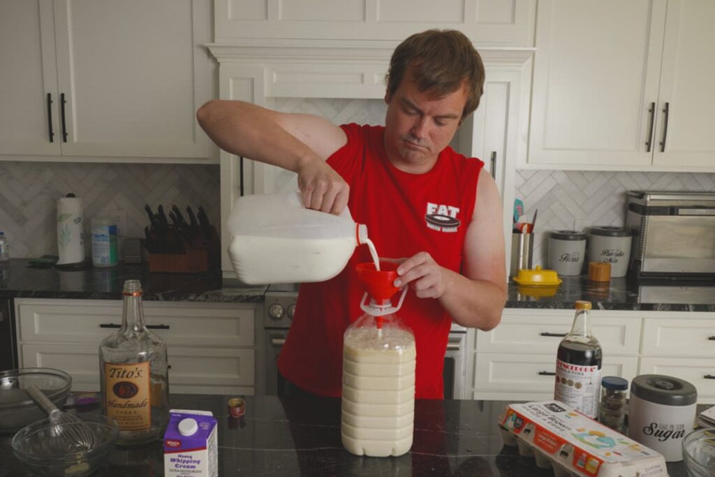 Cook pouring milk through a red funnel into a large jug while making Fight Milk.