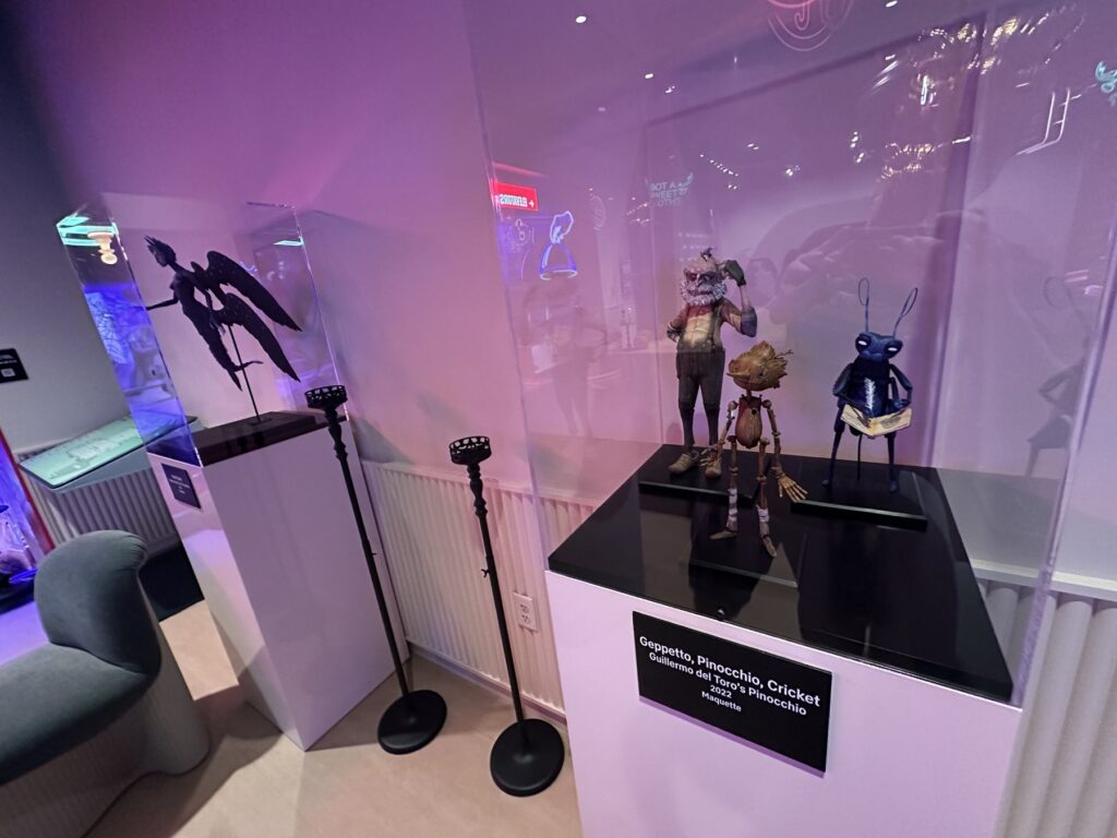 Display case at Netflix Bites Dallas with Geppetto, Pinocchio, and Cricket maquettes from Guillermo del Toro's Pinocchio