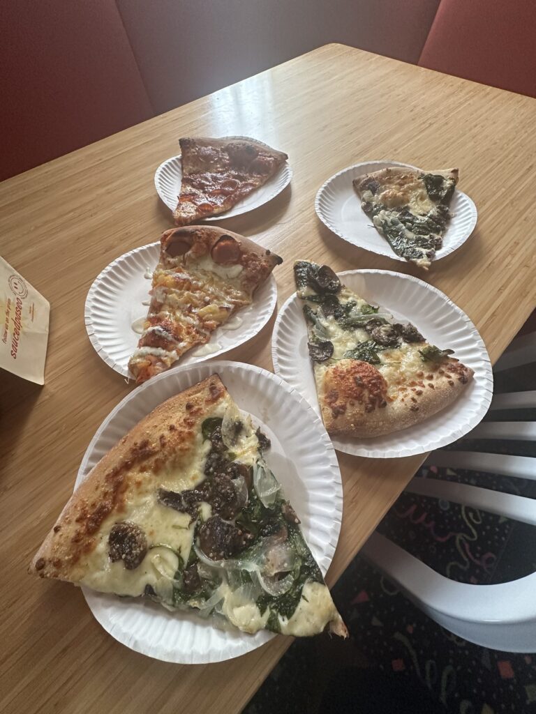 Assorted pizza slices on paper plates at Sauced on Paseo in Oklahoma City.