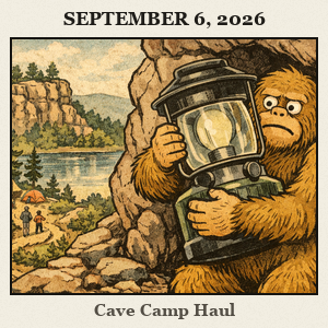 Bigfoot bracing with both hands on a bulky camping lantern at the mouth of a cave, Robbers Cave State Park, with pine trees, rocky bluffs, a lake, and a trail in view.