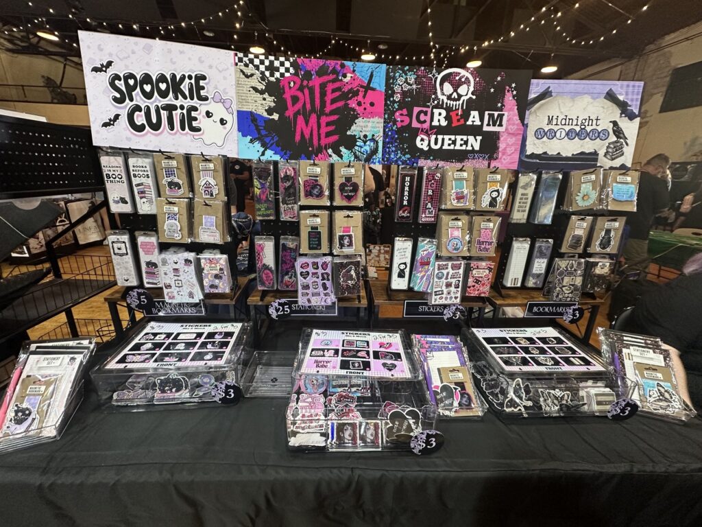 Spooky stationery booth at the Gothic Market Festival with Halloween-themed stickers, bookmarks, and colorful signs.