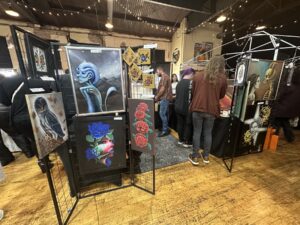 Colorful gothic and surreal paintings displayed on grid panels at the Gothic Market Festival.