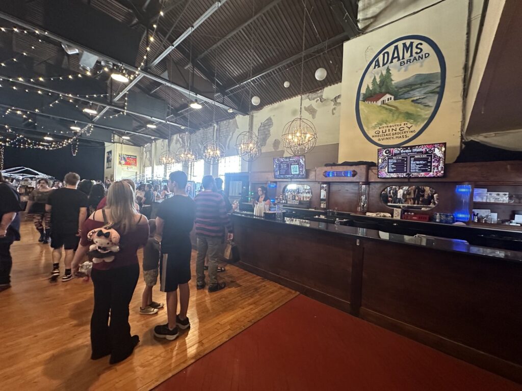 Bar area inside the OKC Farmers Public Market during the Gothic Market Festival with chandeliers and attendees.