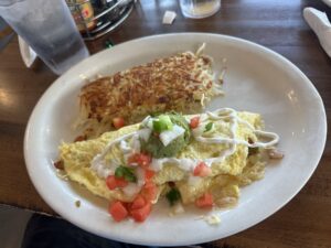Omelet topped with guacamole, pico de gallo, and sour cream with crispy hash browns at Sunnyside Diner in OKC.