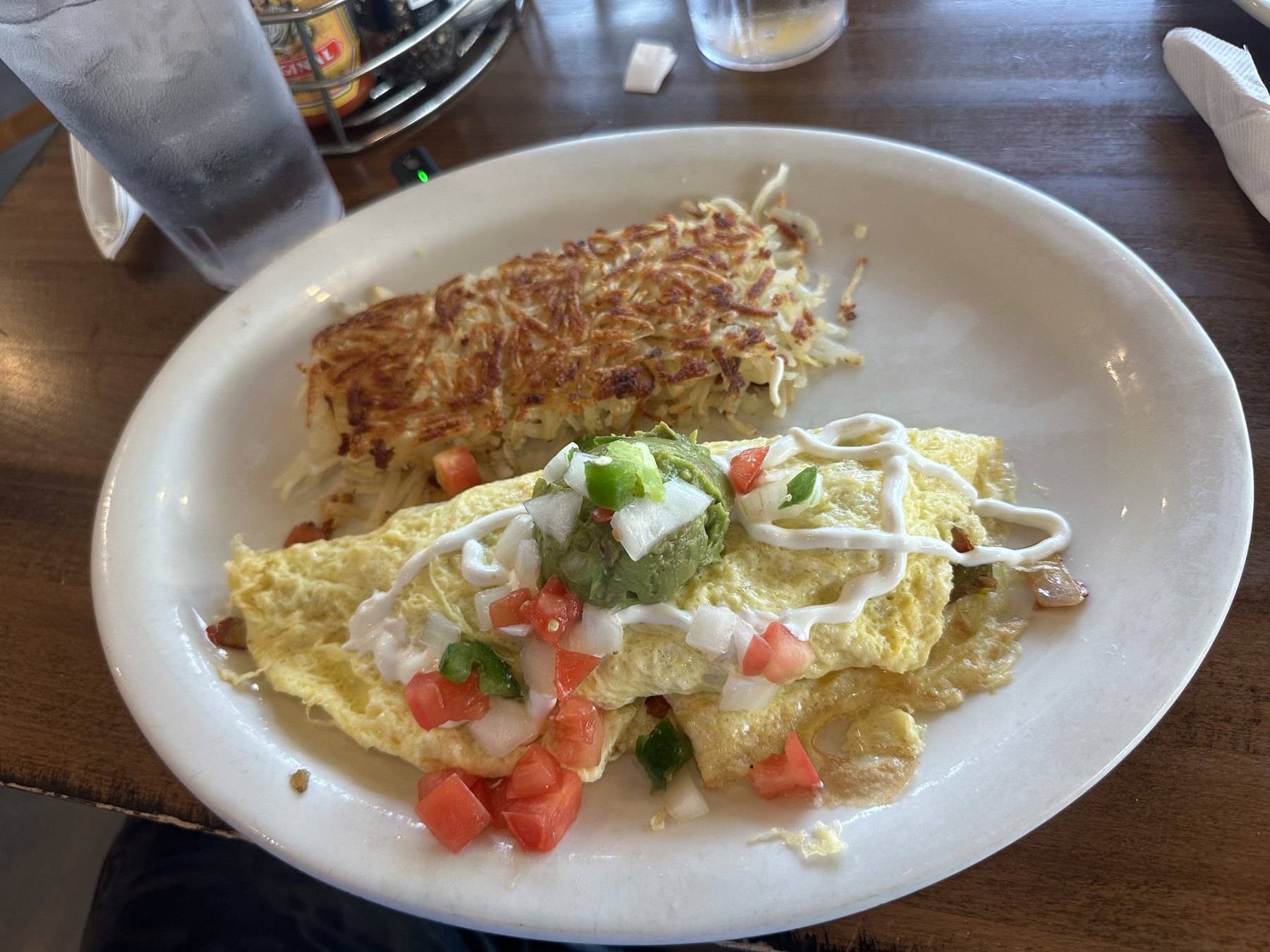 Omelet topped with guacamole, pico de gallo, and sour cream with crispy hash browns at Sunnyside Diner in OKC.