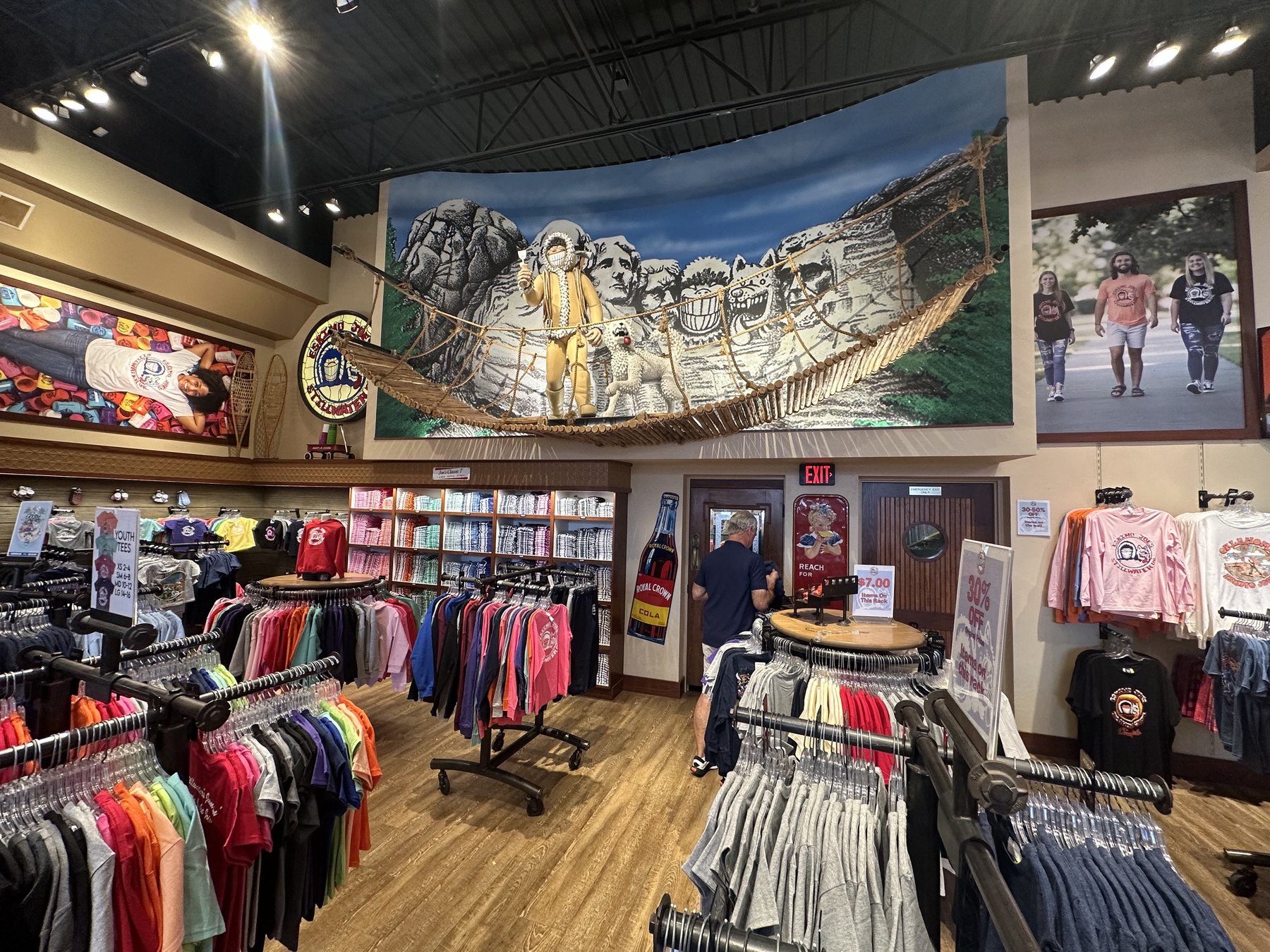 Interior of the Original Eskimo Joe's clothing store in Stillwater Oklahoma with apparel racks and mascot bridge display.