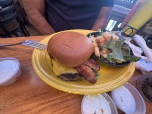 Bacon cheeseburger with a side salad on a yellow plate at Eskimo Joe's in Stillwater, Oklahoma.