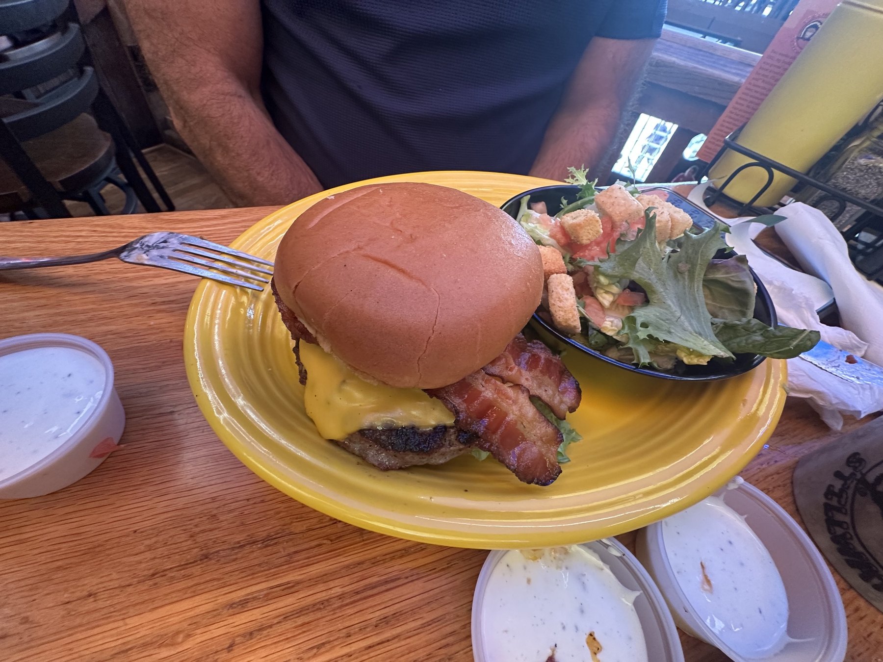 Bacon cheeseburger with a side salad on a yellow plate at Eskimo Joe's in Stillwater, Oklahoma.