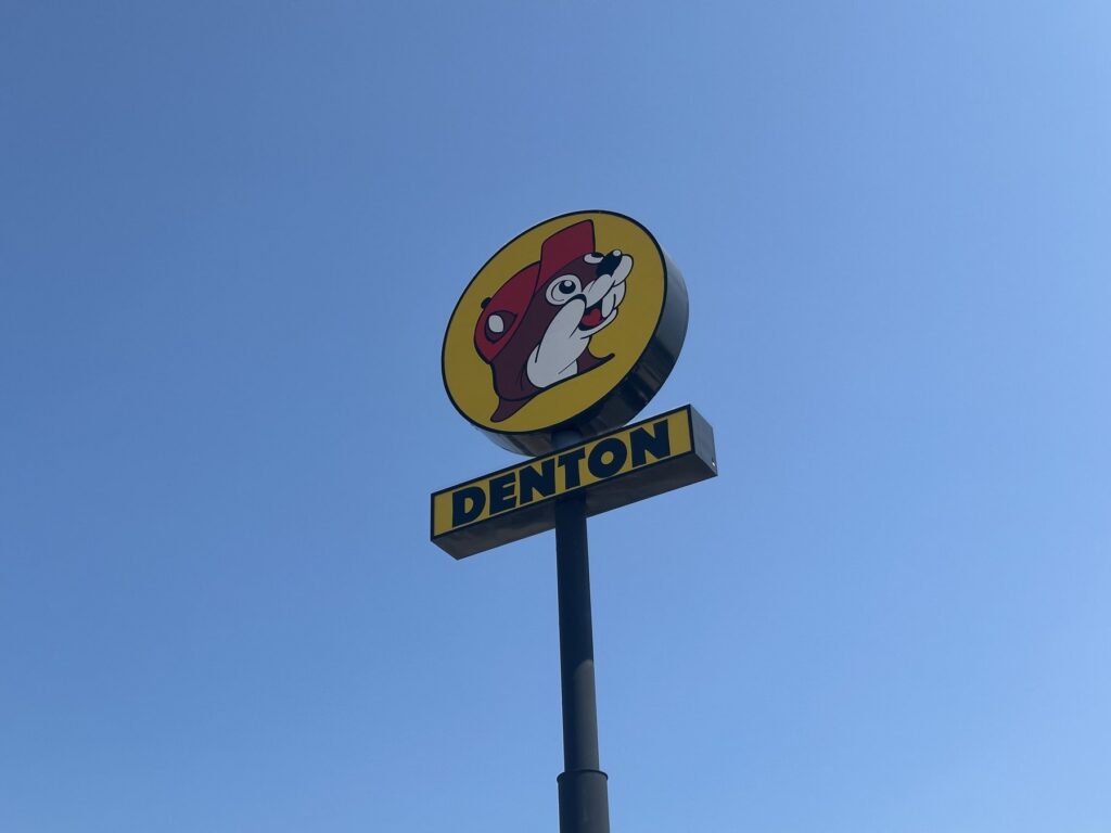 Buc-ee's Denton roadside sign with the beaver logo against a blue sky