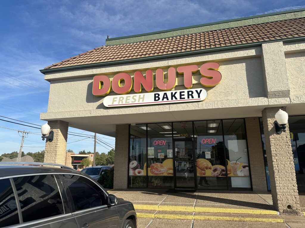 Exterior of an Oklahoma donut shop with a large Donuts Fresh Bakery sign and open signs in the windows.