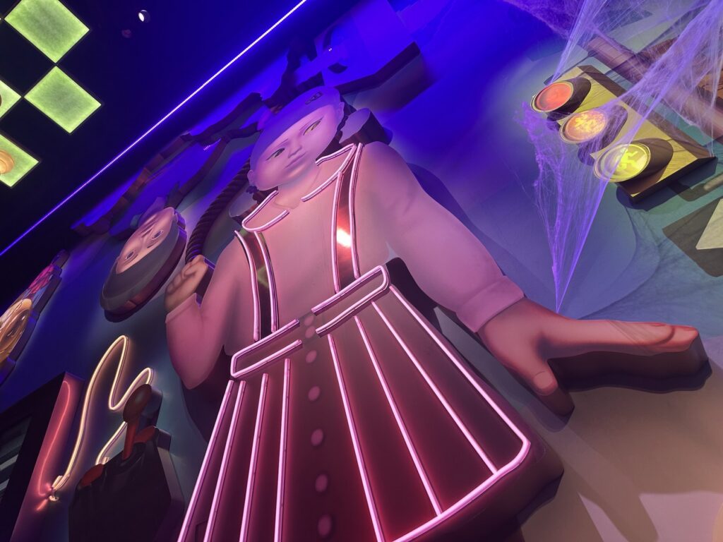 Neon-lit Squid Game doll display inside the Survive the Trials experience at Netflix House Dallas.