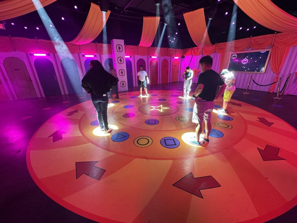 Players standing on lit circles during a Squid Game: Survive the Trials challenge at Netflix House Dallas.