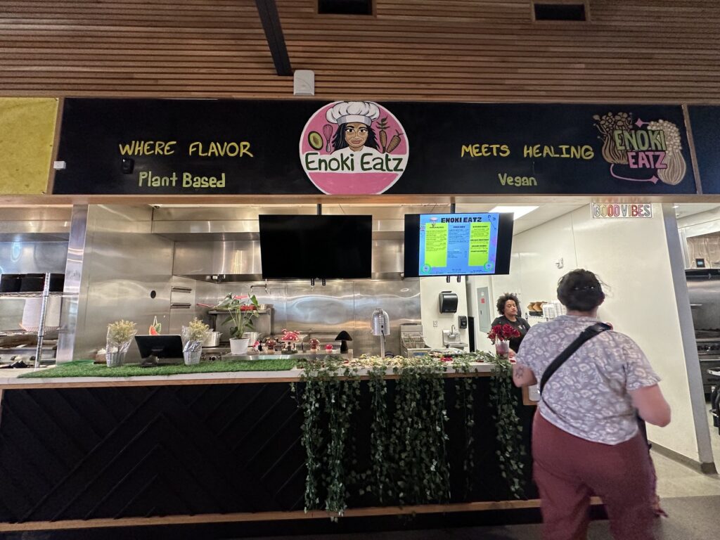 Enoki Eatz counter inside The Collective food hall in Oklahoma City with plant based and vegan signage.