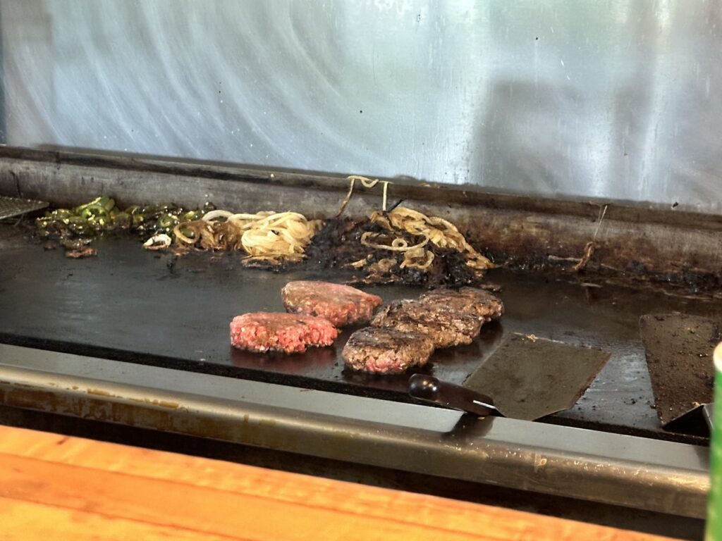 Burger patties cooking on the flat-top grill at Nic's Grill in Oklahoma City