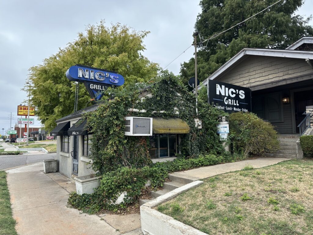 Exterior of Nic's Grill in Oklahoma City with the blue rooftop sign and ivy-covered building