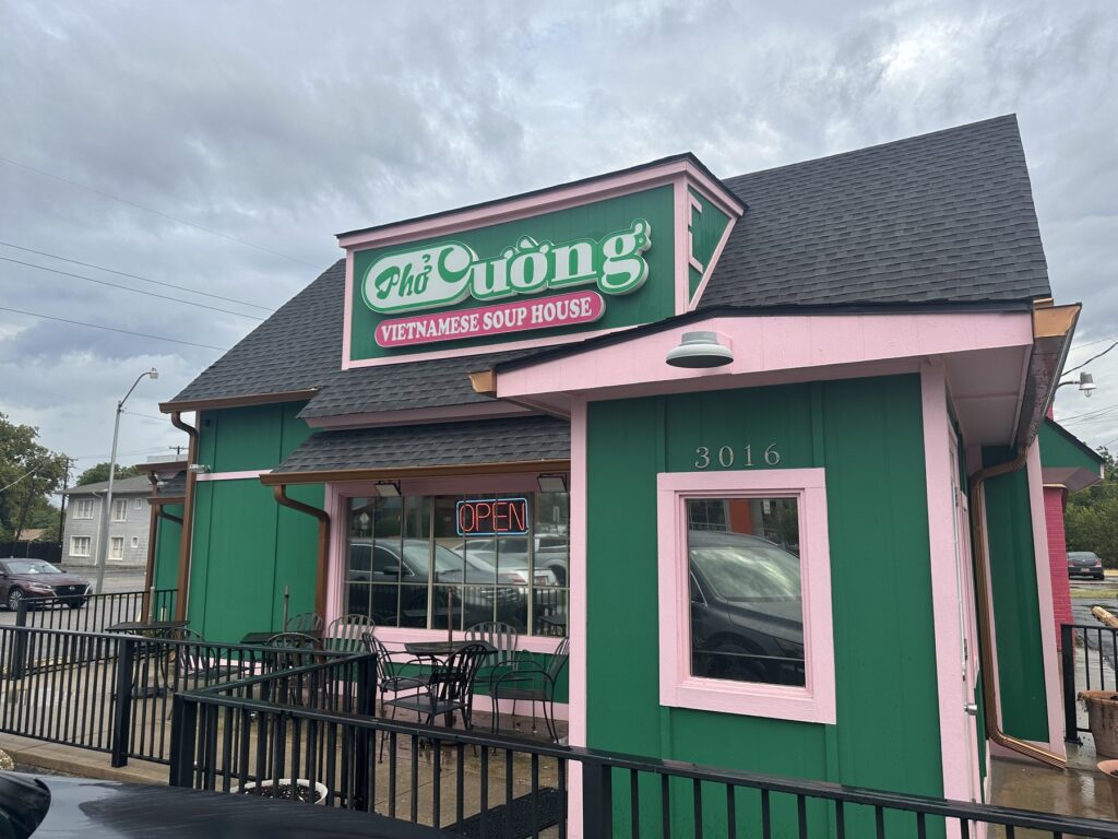 Exterior of Pho Cuong Vietnamese Soup House with green and pink building, restaurant sign, and open sign.