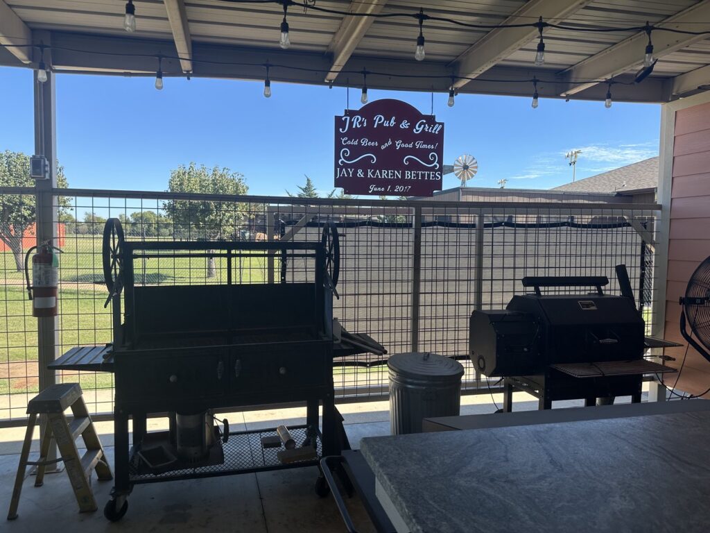 Covered patio at JR’s Pub and Grill with grills, string lights, and a hanging JR’s sign.