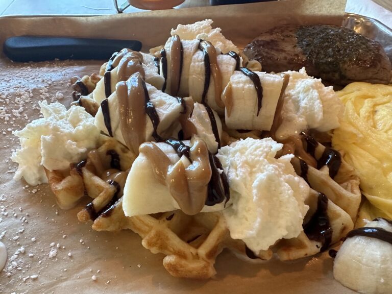 Elvis-style waffle at Just Wafflin’ in Stillwater topped with bananas, peanut butter, chocolate drizzle, and whipped cream