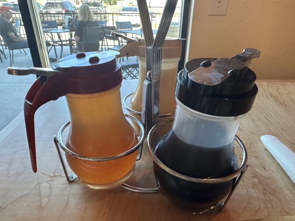 Three syrup dispensers on a table at Just Wafflin’ in Stillwater