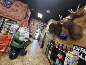 Interior of Cowboy Travel Plaza with a garden gnome statue, mounted animal heads, and Smokey Pokey signage