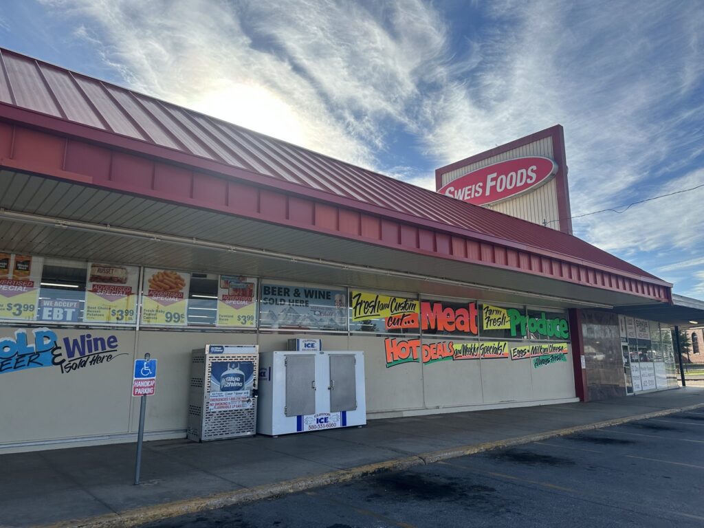 Exterior of Sweis Foods grocery market in Oklahoma City with signs for meat, produce, beer, wine, and groceries