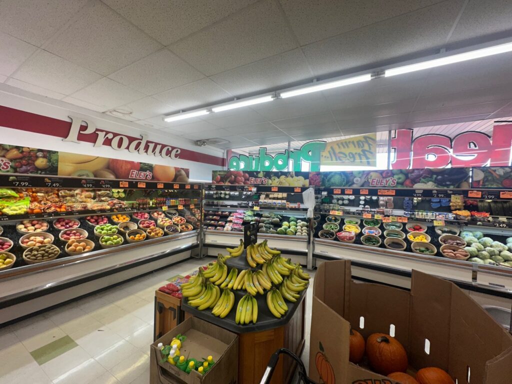 Produce section inside Sweis Foods with bananas, apples, vegetables, and pumpkins