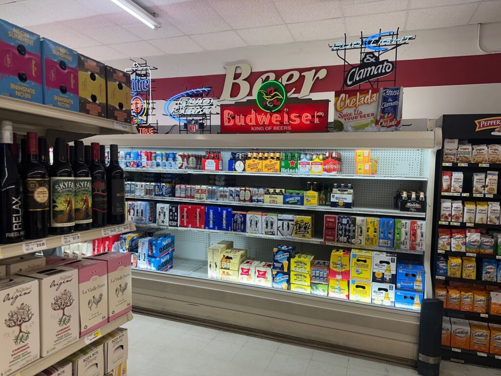 Beer and wine section inside Sweis Foods with refrigerated beer, wine bottles, and neon signs
