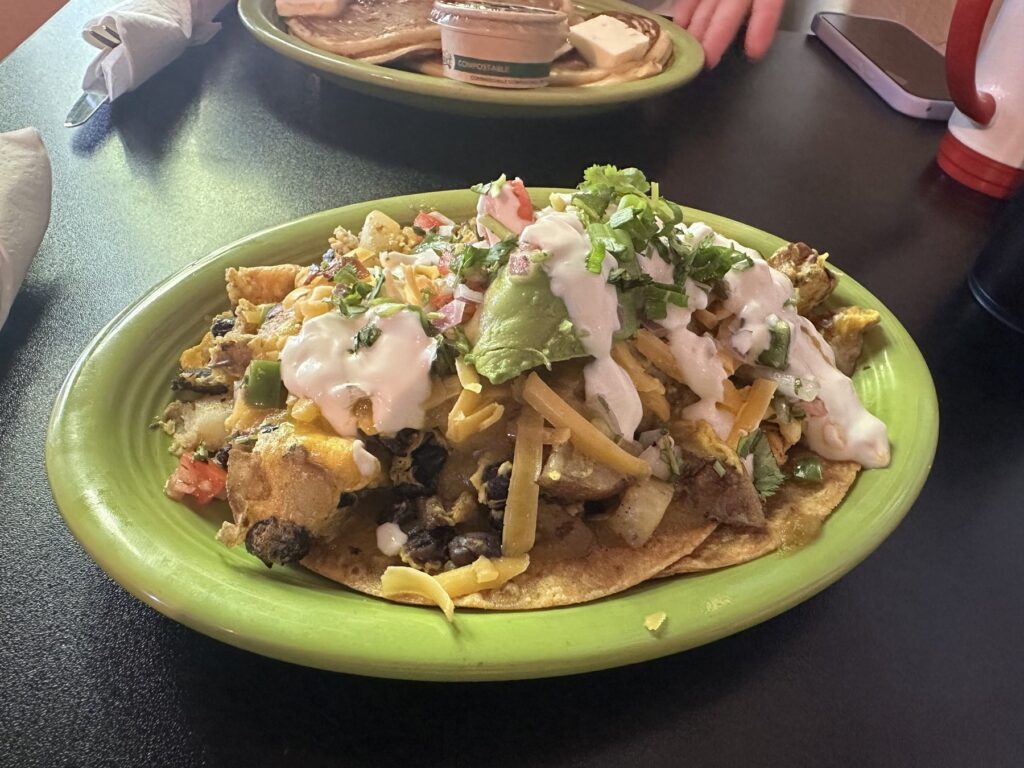 Savory vegan breakfast plate with potatoes, black beans, avocado, cheese, and creamy sauce at The Red Cup in OKC.