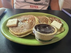 Pancakes with vegan butter and syrup on a green plate at The Red Cup in OKC.