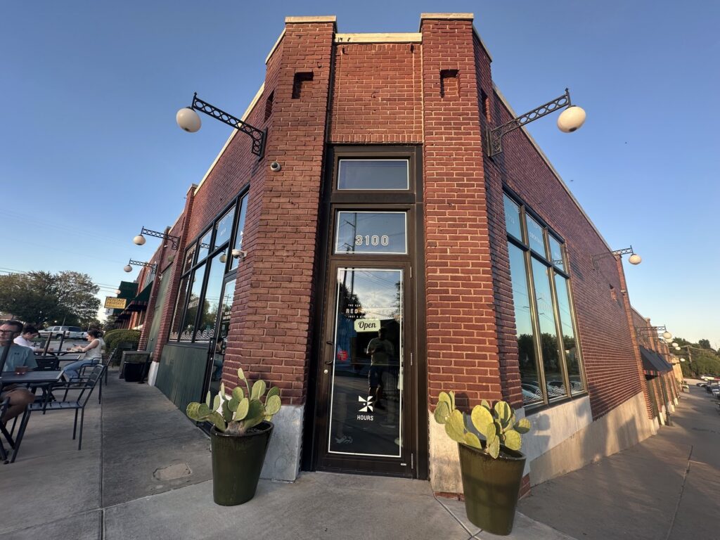 Brick exterior and front door of Red Rooster in Oklahoma City with patio seating outside.