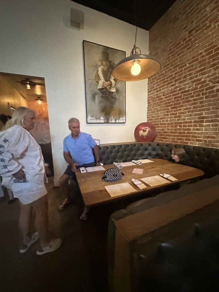 Booth seating with exposed brick walls and pendant lighting at Red Rooster in Oklahoma City.