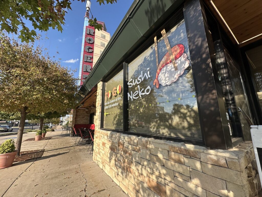 Exterior windows at Sushi Neko with to-go pickup signage and patio seating outside.