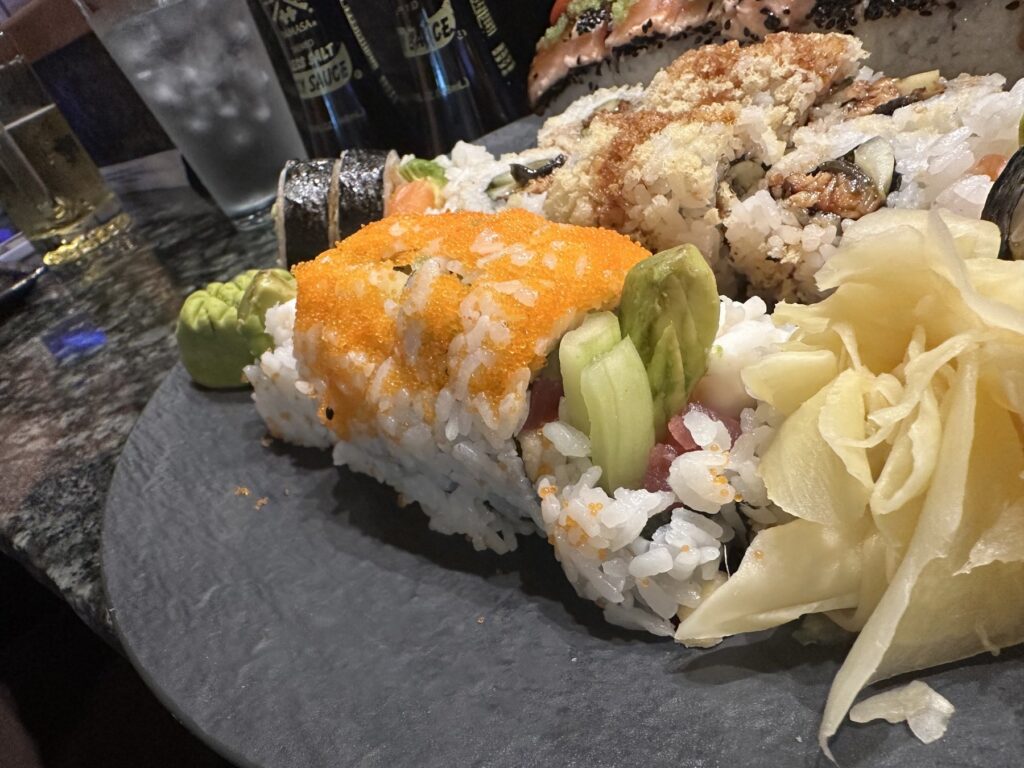 Close-up of an orange roe-topped sushi roll with pickled ginger at Sushi Neko.